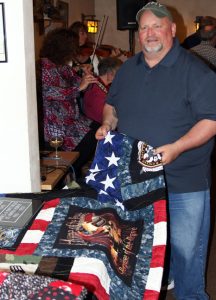 John Smith shows off the military tribute quilt made by Barb Johnson. The qulit raised $1,650 and was donated back. It will be raffled off again during the Veterans Freedom Shoot on May 14. Holly Neumann Photo