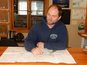 Keith Prust, the owner of Taylor Lake Marina, looks over one of his early color drafts of the cartoon map he drew of the Chain O' Lakes. Robert Cloud Photo