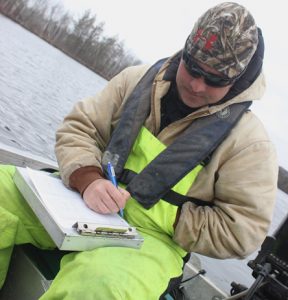 DNR fisheries technician Elliot Hoffman writes down fish measurements as part of a survey of Waupaca County's School Section Lake.  Greg Seubert Photo