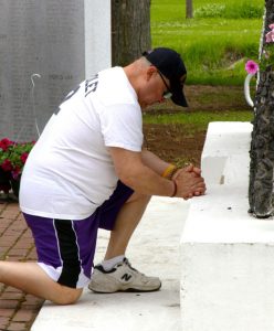 Ron Scott kneels in front of one of the monuments at Sheveland-Taylor Veteran's Memorial Park in Iola and says a prayer for those that have lost their lives while serving in the military.  Holly Neumann Photo