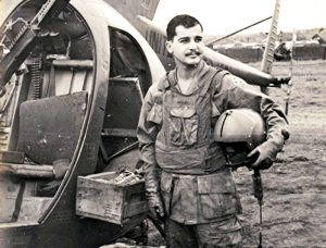 Ron Scott standing by a helicopter he rode on during the Vietnam War.