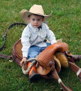 Two-year-old Boyd Gilliand was warming up on dad's saddle before the saddle bronc event. Holly Neumann photo.