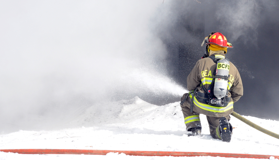 A firefighter battles through a cloud of smoke to put the fire out.