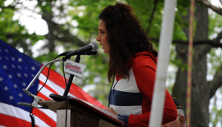 Kayla Lorge sings for the crowd as an American flag waves in the background.